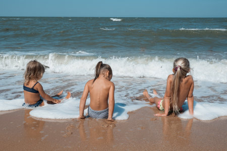 Children swim in the waves, enjoy the holidays. Fun vacation on the beach at the hotel. Friendly family at home and on vacation. High quality photoの写真素材