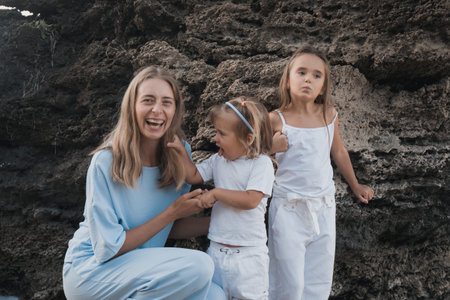 Mothers love. Mom hugs her daughters, kisses and plays, tenderness and care. Friendly family at home and on vacation.の写真素材