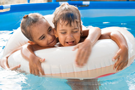 Two European girls, sisters girlfriends on an inflatable circle in the pool play, have fun, enjoy. Family holidays, the joy of holidays and fun on the beach at the hotel. High quality photo.の写真素材