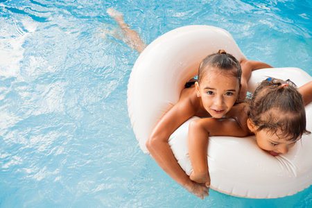 Two European girls, sisters girlfriends on an inflatable circle in the pool play, have fun, enjoy. Family holidays, the joy of holidays and fun on the beach at the hotel. High quality photo.の写真素材