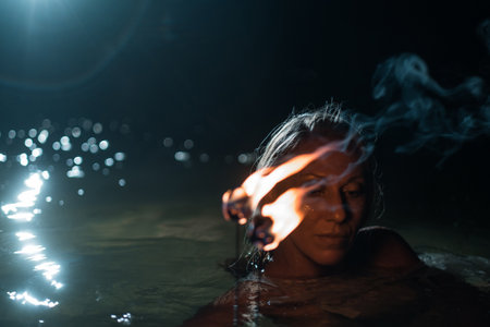 Caucasian woman dancing with fire in the water. Fire show at sea. Acrobatics on the beach. Yoga and relaxation at sunset. Spectacular circus performance. model body. High quality FullHD footage.の写真素材