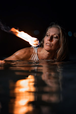 Caucasian woman dancing with fire in the water. Fire show at sea. Acrobatics on the beach. Yoga and relaxation at sunset. Spectacular circus performance. model body. High quality FullHD footage.の写真素材