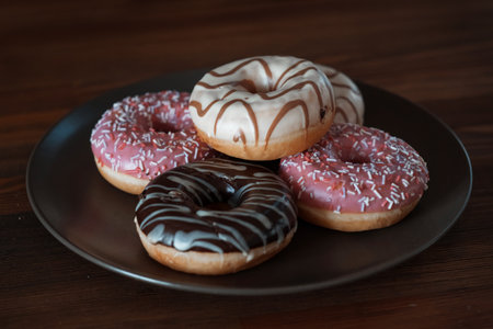 multi-colored, white, pink, chocolate donuts lie on a brown plate. Vegetarian breakfast, sweet. High quality photoの写真素材