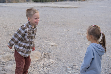 a girl in a gray hoodie and a boy in a plaid shirt play outside. High quality photoの写真素材