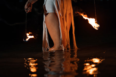 Caucasian woman dancing with fire in the water. Fire show at sea. Acrobatics on the beach. Yoga and relaxation at sunset. Spectacular circus performance. model body. High quality FullHD footage.の写真素材