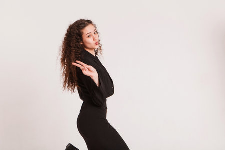 fashion female portrait. Girl, curly girl with black hair in a strict business suit on a white background. High quality photoの写真素材