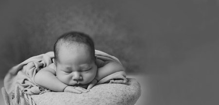 A newborn baby is wrapped in diapers with a wool cap in a basket. Swaddling, maternity hospital, family, life planning, parenting. A mothers love for her child.の写真素材