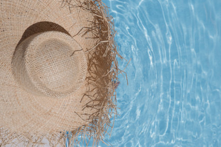 A straw hat with a large brim on the background of a blue pool. Sea, beach, vacation, warm weather, travel.の写真素材