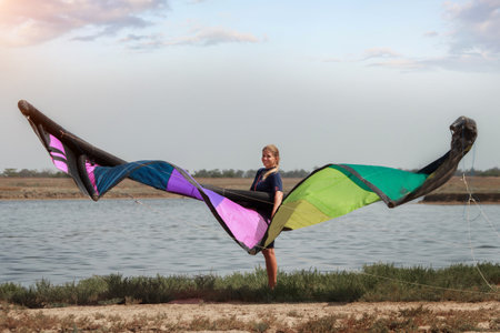 A woman with a multicolored parachute, an athlete riding kitesurfing on a blue shore. Beach, active recreation. Sunset, parachute, board, freedom.の写真素材