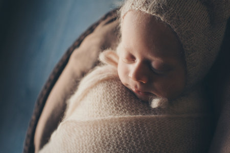 A newborn baby is wrapped in a wool blanket with a wool cap in a basket. A mothers love for her child.の写真素材