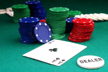 cards and stack of Poker chips and dealer button on a green background