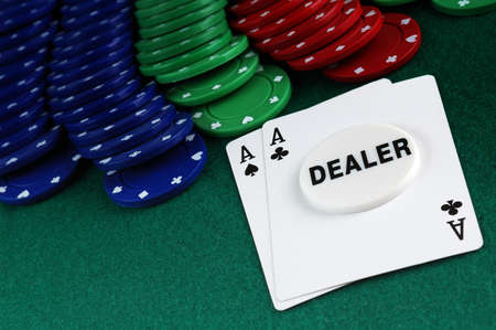 cards and stack of Poker chips and dealer button on a green background