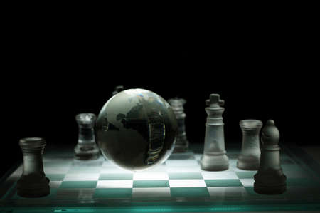 Crystal chess pieces on a row with a globe  On black background  の写真素材