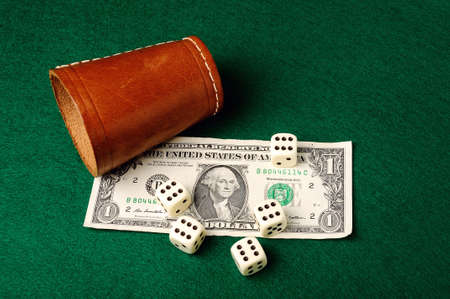 Dices, leather cup and dollar bill   on green clothの写真素材
