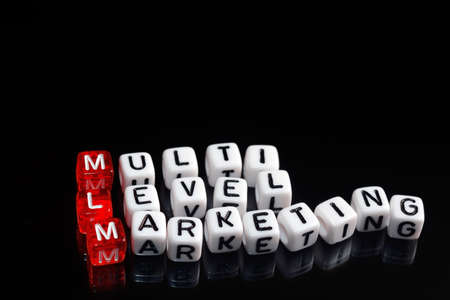 MLM Multi Level Marketing written on dices on black  backgroundの写真素材