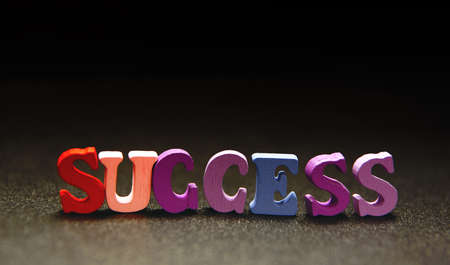 success - word made from multicolored child toy  letters on black backgroundの写真素材