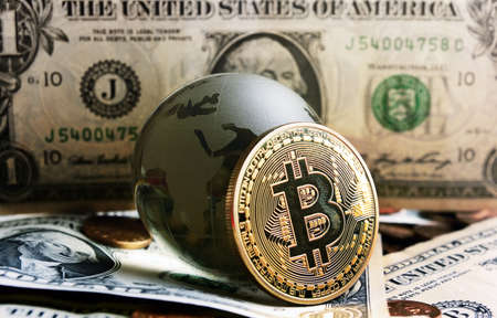 bitcoin coin and cristal globe over  one dollar banknote