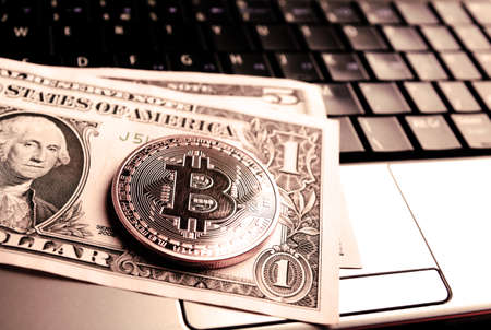 bitcoin coin and one dollar banknote on laptop keyboardの写真素材