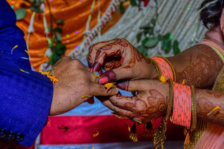 Engagement Ceremony; Indian bride putting a wedding engagement ring on finger of groom.の写真素材