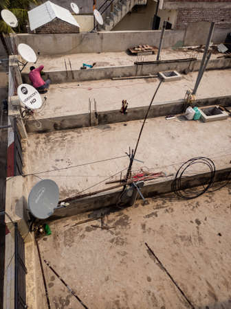 Maharashtra,India-03/28/2021- Series of DTH installed on roof - Dish TV, Videocon d2h, Airtel, Videocon HD. Installation engineer is installing DTH setup.のeditorial素材