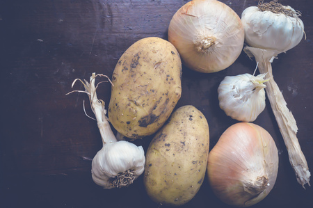 potato, onion and garlic on wooden tableの写真素材