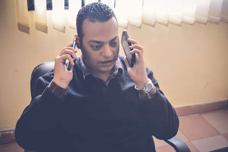 Busy business man holding two mobiles