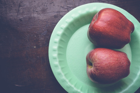 top view of two apples on green plate on wooden tableの写真素材