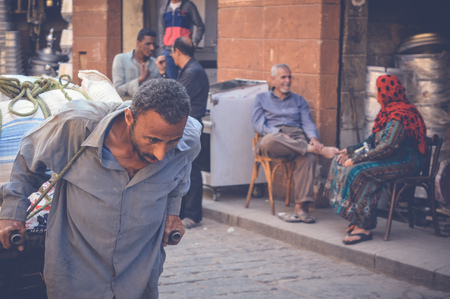 cairo, egypt, april 15, 2017: poor man carry things on his back at muizz streetのeditorial素材