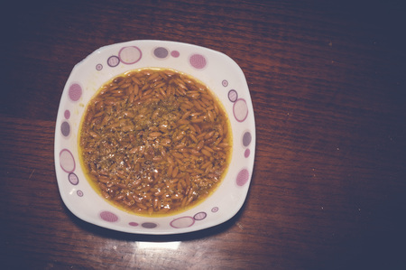 orzo noodle soup in white bowl on wooden tableの写真素材