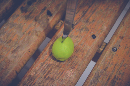 closeup of human cutting lemon on wooden tableの写真素材