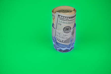 Dollars onto green background rolled in a glassの写真素材