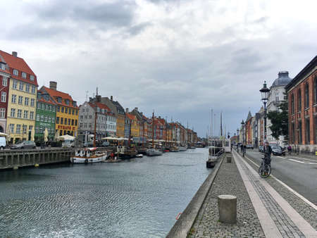 Copenhagen, Denmark. September 26, 2018:  Nyhavn street with Danish bars, restaurants and boats in the canal. The old buildings are painted in vibrant colours which make them more attractive on the cloudy days.のeditorial素材