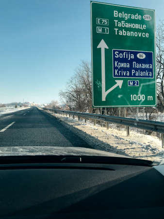 On a highway in North Macedonia with Belgrade and Athens signs in frontの写真素材