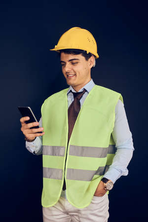 Young engineer with mobile phone and helmet
