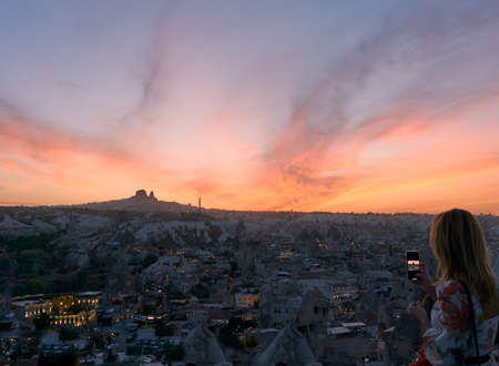 Goreme, Cappadocia / Turkey - October 24, 2020: Panoramic cityscape photo of Goreme Town in Nevsehir, Turkey. Tourist looking at the wonderfull sunset view and takin photo.のeditorial素材