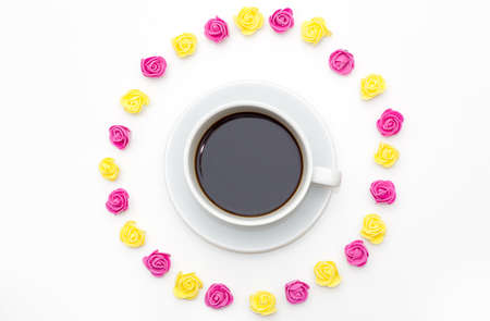 Cup of black coffee pink yellow roses laid out around on a white background. romantic love background for Valentine's day, birthday, holiday, party, weddingの写真素材