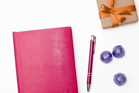 pink diary, pen, some chocolate in a blue wrapper and gift box on white background. business minimal concept for women. Flat lay, top view.の写真素材