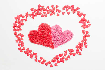 red heart next to the pink heart made of small decorative hearts on white background. festive...