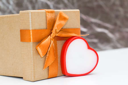 gift box and heart on a white table on a grey background. romantic love background for Valentine's day, birthday, holiday, party, wedding.の写真素材