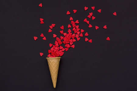 waffle cone and a lot of small hearts on a black background romantic love background for Valentine's day, birthday, holiday, party, wedding. Flat lay.の写真素材