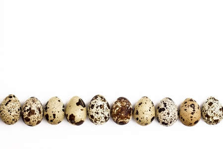 quail eggs to the bottom on a white background. Easter festive background. Flat lay.の写真素材