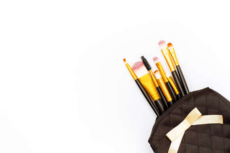 makeup brushes in black cosmetic bag on white background. Flat lay. Top view.