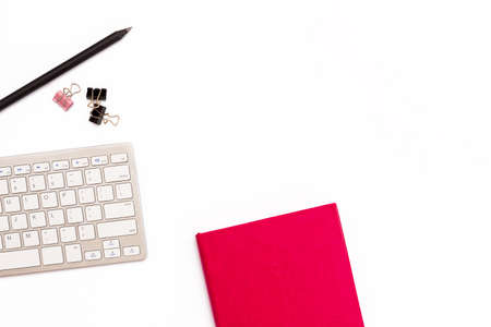 Pink diary, keyboard, and pencil on white background. Flat lay concept of the workplace in the office for female. Top view.の写真素材