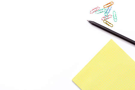 Yellow Notepad, black pen and colorful paper clip on white background. Minimal working concept for office, school, university. Flat lay. Top view.の写真素材