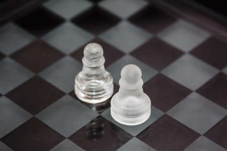 chess pieces made of glass: a confrontation between two pawns against a black background. Minimal business concept.の写真素材