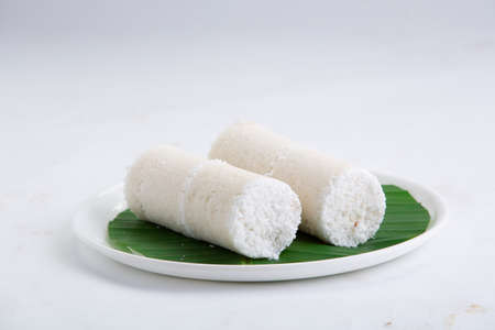 Puttu,steam cake ,white raw rice puttu , pacharisi maavu puttu _breakfast item made using rice flour which is very healthy and arranged in white plate lined with banana leaf on white background.の写真素材