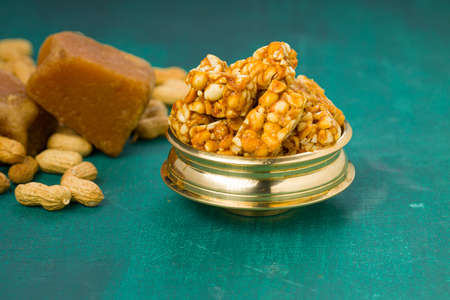 Peanut bar,crunchy sweet peanut bar which is very healthy and tasty snack,arranged in a brass vessel with peanut and jaggery on the dark green colour  background,selective focus.の写真素材
