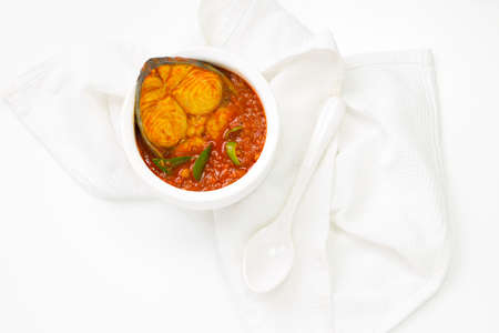 Seer Fish curry, traditional Indian fish curry ,kerala special ,arranged in a white bowl garnished with curry leaves and fresh green chilli on a white textured background,isolated.の写真素材