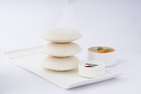 Idly or Idli, south indian main breakfast item  which is beautifully arranged on white rectangle...