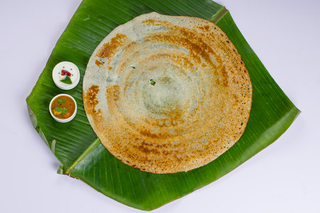 Dosa _Ghee roast Dosa,famous south Indian breakfast item which is made in caste iron pan in traditional way and arranged on afresh green banana leaf with side dish  ,on a white background ,isolated.の写真素材